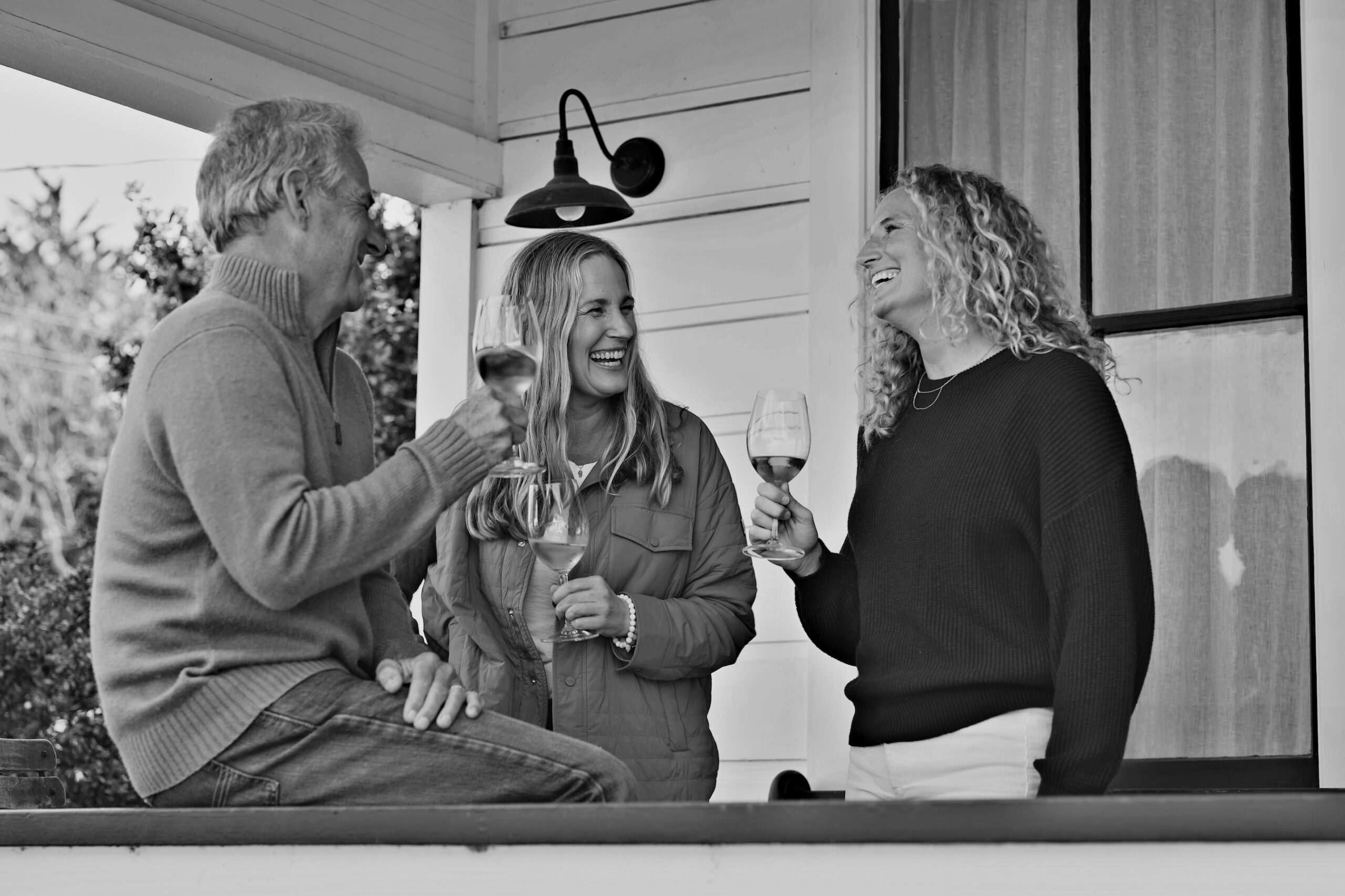 three people enjoying wine on porch