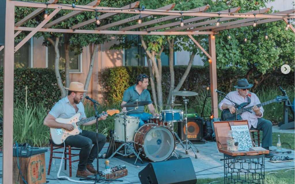 A band playing instruments underneath a pergola