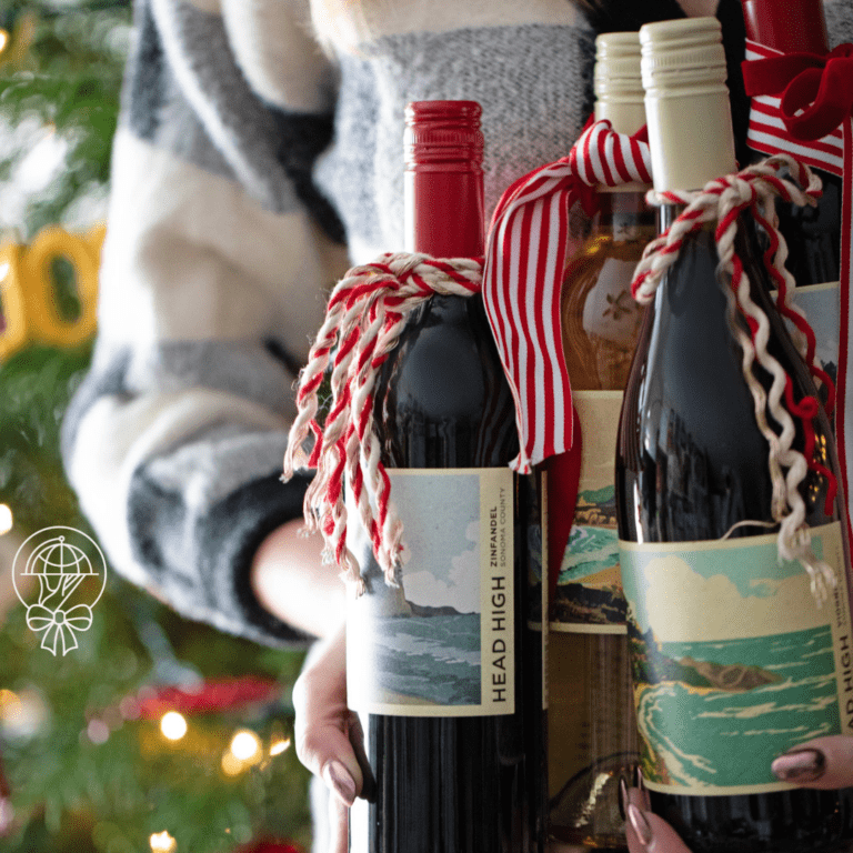 Someone holding wine bottles as a gift wrapped in ribbon